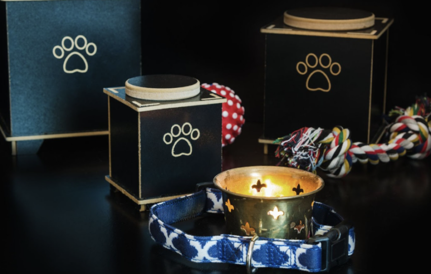 黑色寵物骨灰罈與寵物遺物，包括項圈、玩具球和點燃的小蠟燭